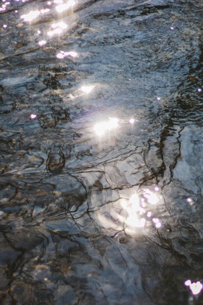 A close-up of water with sunlight reflection creating a rippled texture, Schweiz.
